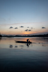 Fototapeta premium Fishermen row a wooden boat looking for fresh water fish in the river