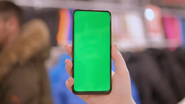 Mall. Use green screen for copy space closeup. Chroma key mock-up on smartphone in hand. hold mobile phone and looking photos or pictures