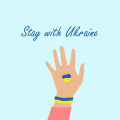 The concept of support for Ukraine, Stay with Ukraine. The hand is raised up, a yellow-blue heart in the palm.