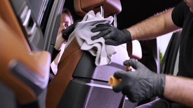 Professional car washer in black gloves wipes the car after washing and lining ceramics. Concepts of: Professional work, Various washing tools, Cleaning to shine.