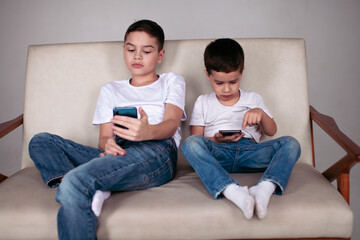 two brothers sitting on the sofa with phones