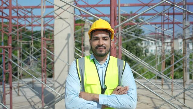Asian young engineer in construction site looking at camera and smiling friendly.