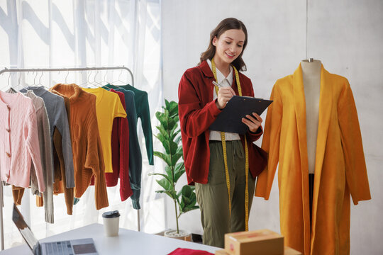 Concept of fashion and designer,Woman fashion designer stylish with measuring tape working about fashion design while holding sample desing product prototype compare with mannequin in workshop studio.