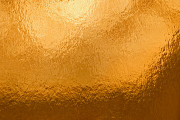 
Gold background, texture. Background of gold foil with light reflections. 