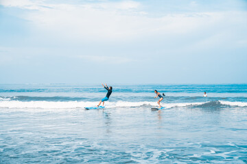 Naklejka premium The man is surfing. A novice surfer on the waves in the ocean off the coast of Asia on the island of Bali in Indonesia.