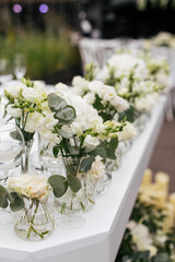 Close up of a wedding table decoration with vases of white flowers and eucalyptus. Wedding outdoor and floristic concept 