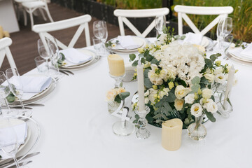 Served wedding table with decorative fresh white flowers and candles. Celebration details. Hanging flower beds and light bulbs Wedding decoration and decor, floristic concept