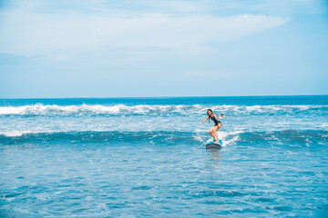 A woman is surfing. A surfer on the waves in the ocean off the coast of Asia on the island of Bali in Indonesia. Sports and extreme. Beauty and health. Fashion and beach style.