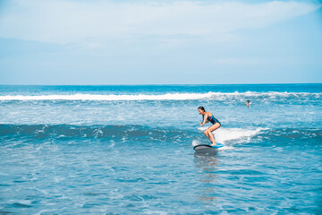 A woman is surfing. A surfer on the waves in the ocean off the coast of Asia on the island of Bali in Indonesia. Sports and extreme. Beauty and health. Fashion and beach style.