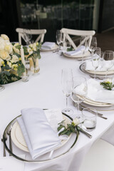 Served wedding table with decorative fresh white flowers and candles. Celebration details. Hanging flower beds and light bulbs Wedding decoration and decor, floristic concept