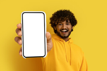 Obraz na płótnie Canvas Positive young indian man showing huge smartphone, mockup