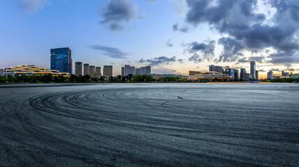 Asphalt road and city skyline with modern buildings at sunset in Ningbo, Zhejiang Province, China.