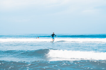 Surfing. A surfer on the waves in the ocean off the coast of Asia on the island of Bali in...
