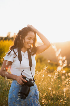 Happy woman with photo camera in sunny field