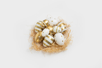 Obraz premium Decorative Easter eggs and straw on a white background