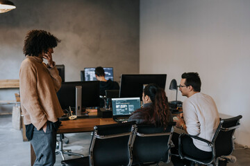 Businesswoman discussing with male and female programmers working on laptop at desk