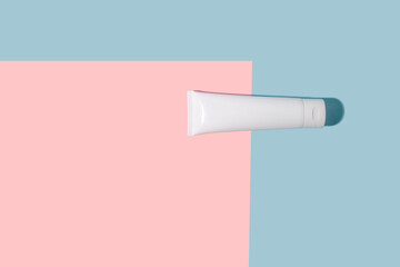 White cosmetic tube of cream with a hard shadow on a pink and blue background.