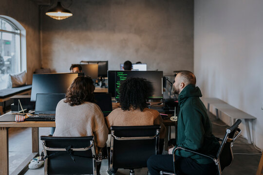 Female and male programmers coding on computer while working at startup company