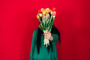 International Women's Day. a happy woman in a bright green dress holds a bouquet of flowers near her face.
