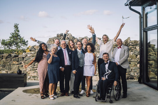 Portrait Of Cheerful Family Enjoying Wedding Ceremony On Deck Against Sky