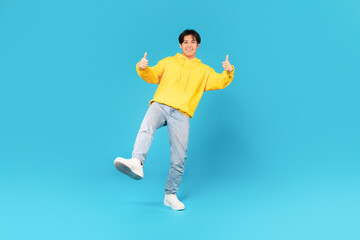 Fototapeta na wymiar Asian Male Teen Gesturing Thumbs Up With Both Hands, Studio
