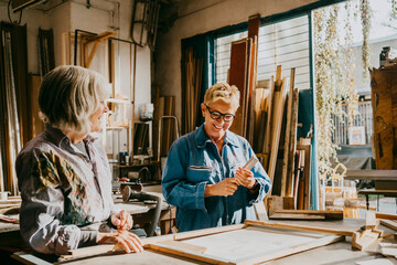 Smiling senior female carpenters talking while working at workshop