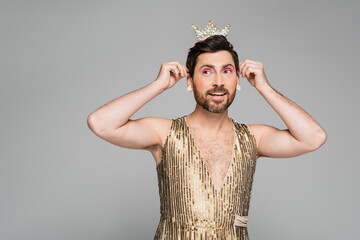 cheerful man wearing toy crown on head while standing in princess dress costume isolated on grey. © LIGHTFIELD STUDIOS