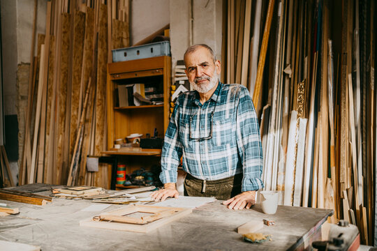 Portrait of confident male carpenter standing in repair shop