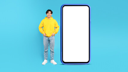 Korean Teen Guy Near Big Phone Standing On Blue Background