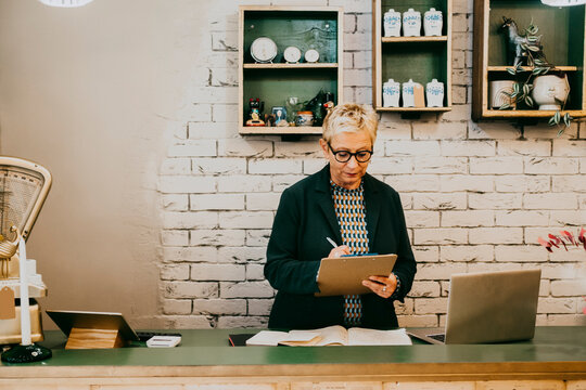 Senior female owner preparing checklist while working at interior shop