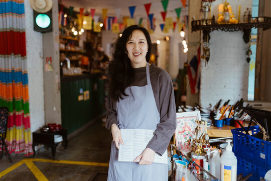 Portrait of smiling female owner holding menu card while standing at restaurant - Powered by Adobe
