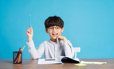 portrait of school boy sitting and studying on a blue background