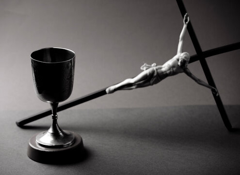 Christian chalice silhouette with crucifix on the table, black and white photography