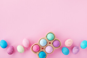 Easter holiday composition. Top view photo of colorful Easter eggs in knitted basket on pink table.