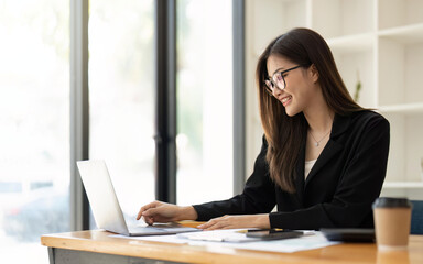 Asian Business woman using calculator and laptop for doing math finance on an office desk, tax, report, accounting, statistics, and analytical research concept