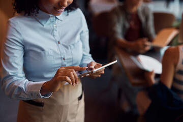 Close up of African American waitress using touchpad while working in cafe.