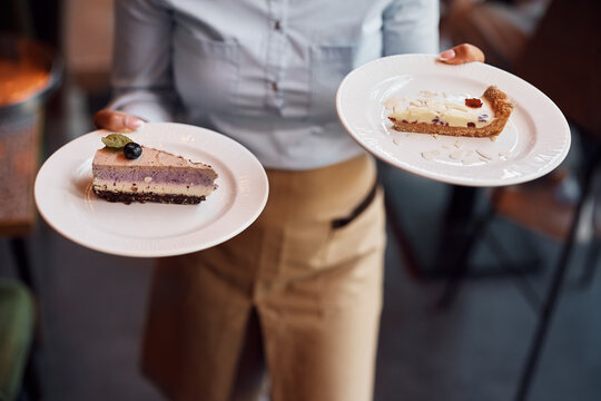 Close up of waitress serving dessert in cafe.