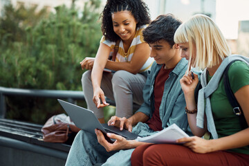 Multiracial group of happy university friends e-learning on laptop at campus.