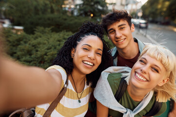 Group of cheerful college friends taking selfie and looking at camera.