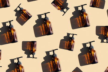 Pattern made with brown glass bottle with pump of cosmetic products and strong shadow on beige background, as a backdrop or texture. Creative layout for your design