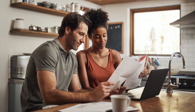 Our Debt Is Almost Paid Off. Cropped Shot Of A Couple Using Their Laptop And Going Through Paperwork At Home.