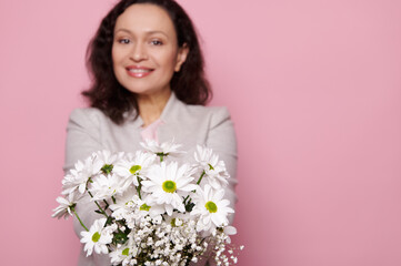 Cute spring bouquet of white chrysanthemums and gypsophila flowers, in hands of a blurred charming...