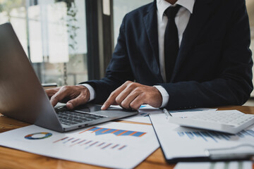 Businessman hands working on laptop computer with market report document and management business project, Business accounting concept.