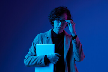 Obraz premium man with a laptop in his hands and a jacket, smile, glasses in blue light, Blue Perennial color, cyber security, technology, laptop copy space, trend neon, freelancer, purple light