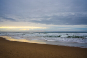 Dramatic sunset on the beach. Wide sandy beach, stormy sea, and beautiful cloudy sky, copy space