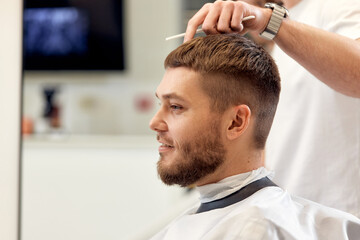 Obraz na płótnie Canvas man visiting professional hairstylist in barber shop