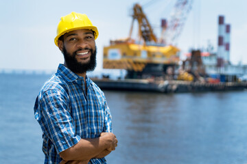 Black offshore worker with digger and ocean