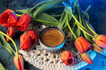 A cup of coffee on the table with a bouquet of red tulips. breakfast on women's day