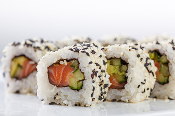 Sushi with salmon on a white plate with wasabi, ginger, soy, chopsticks on a white background