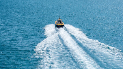 Barco amarillo que actua como practico en el puerto de Barcelona, navegando en un mar azul